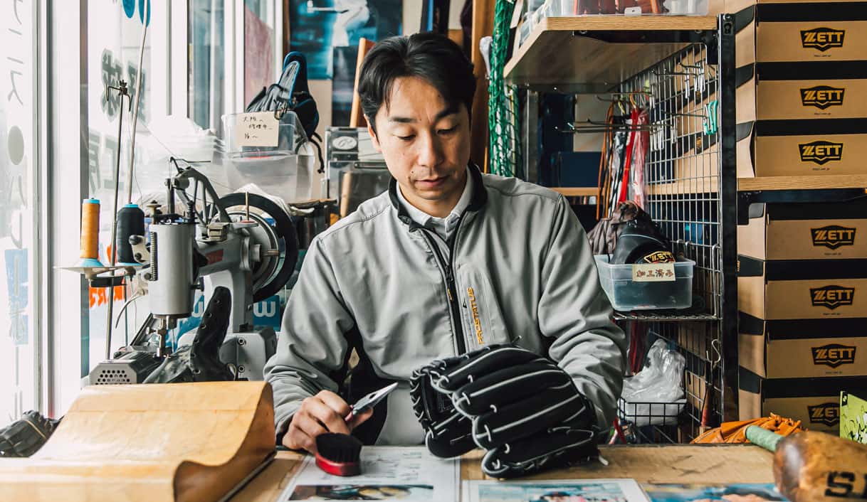 使い込まれたグラブを作業台で修理する職人