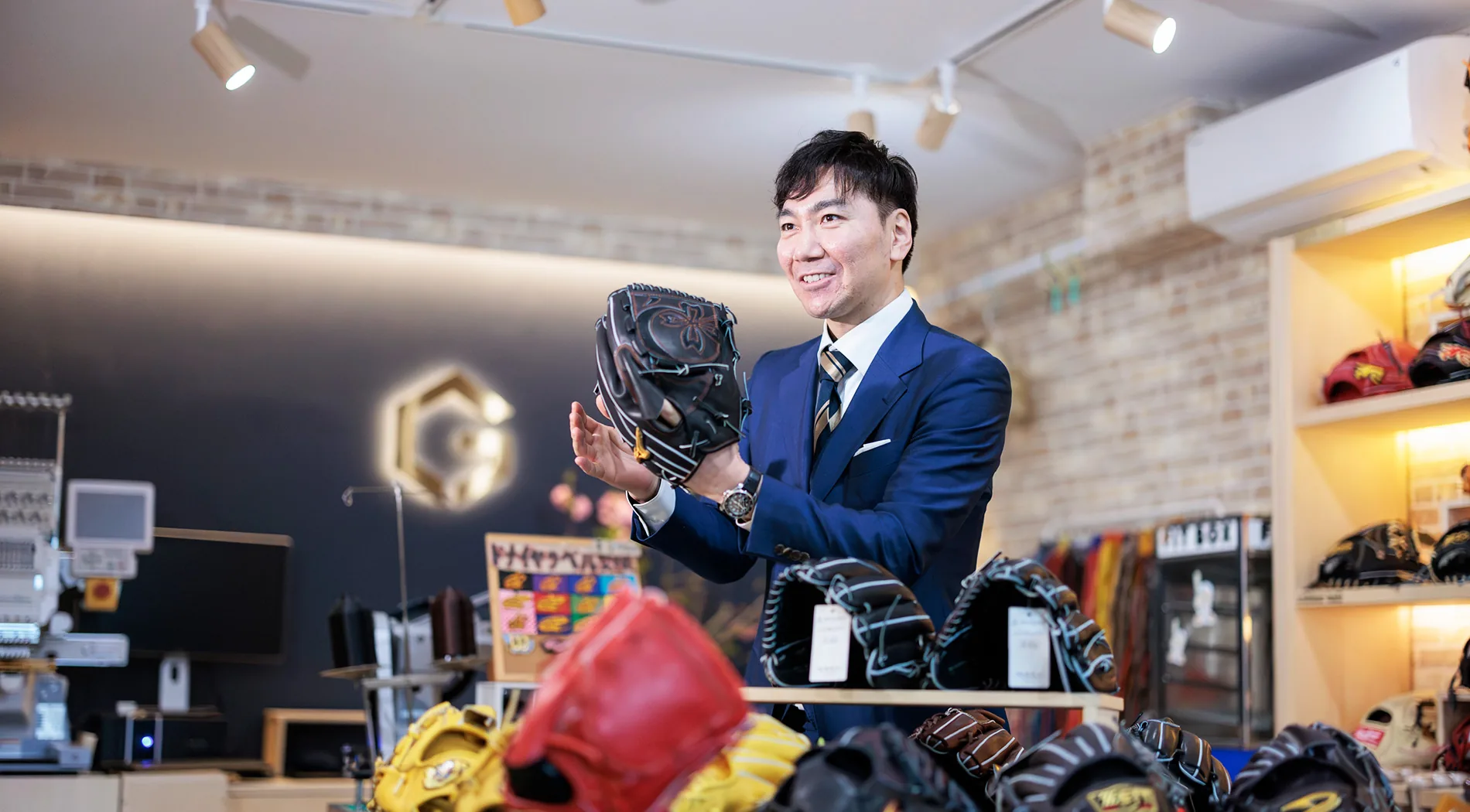 明るいグラブ売り場でグラブを持つスタッフ