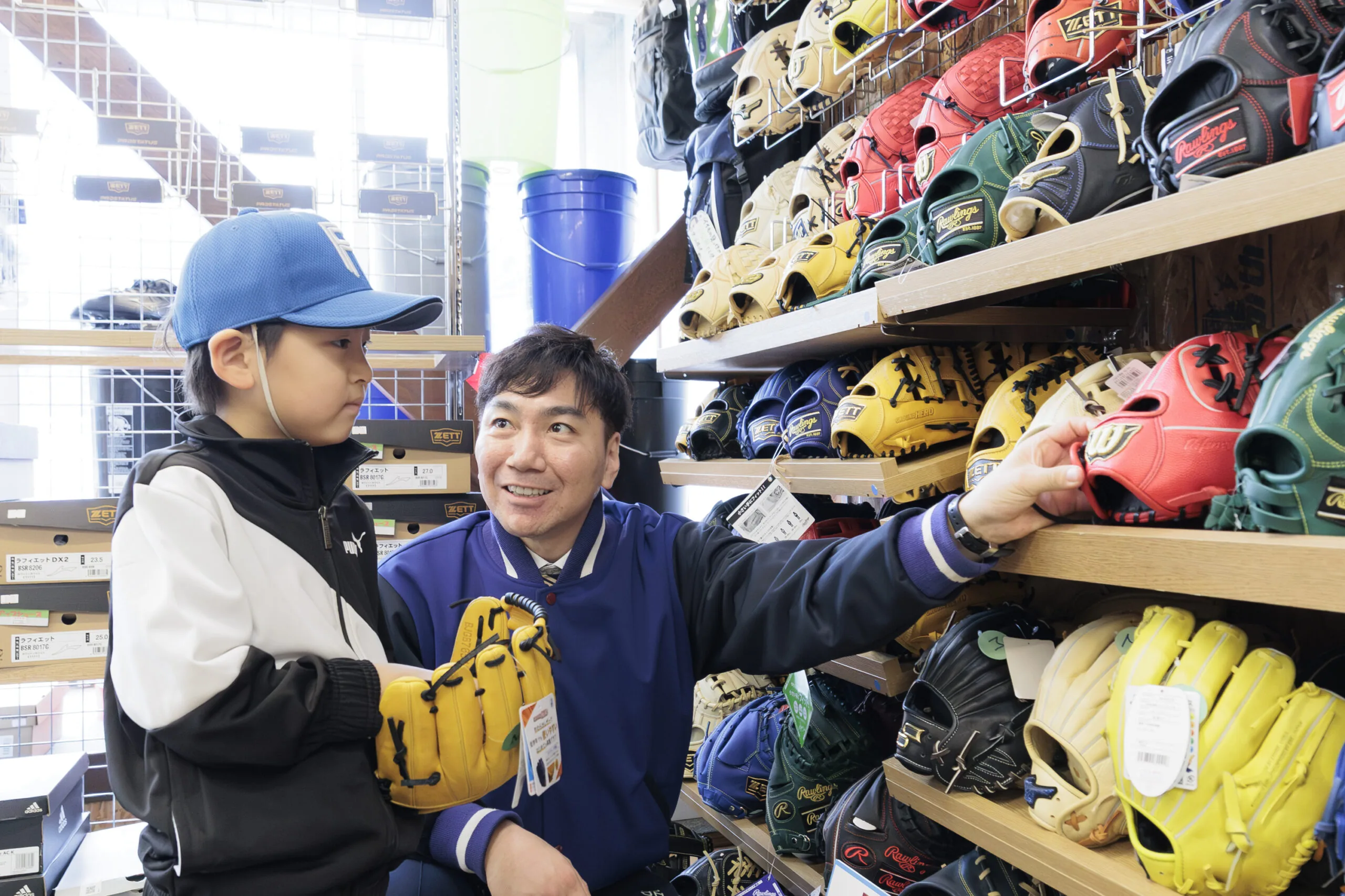 グラブ売り場で、男の子と目線を合わせて相談にのる古内のスタッフ